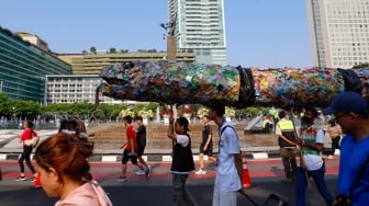 Aktivis lingkungan dari komunitas Aksi Muda Jaga Iklim membawa replika paus dan naga yang terbuat dari sampah plastik di kawasan Bundaran HI, Jakarta, Minggu (27/10/2024). [Suara.com/Alfian Winanto]