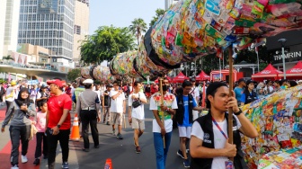 Aktivis lingkungan dari komunitas Aksi Muda Jaga Iklim membawa replika paus dan naga yang terbuat dari sampah plastik di kawasan Bundaran HI, Jakarta, Minggu (27/10/2024). [Suara.com/Alfian Winanto]