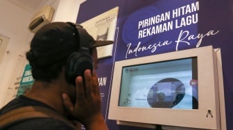 Pengunjung mendengarkan piringan hitam lagu Indonesia Raya yang ditampilkan di Museum Sumpah Pemuda di Jakarta, Senin (28/10/2024). [Suara.com/Alfian Winanto]