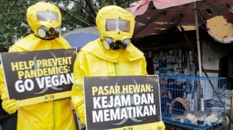 Aktivis dari People for the Ethical Treatment of Animals (PETA) menggunakan alat pelindung diri (APD) berjalan di Pasar Hewan Jatinegara, Jakarta, Selasa (12/11/2024). [Suara.com/Alfian Winanto]