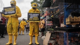 Aktivis dari People for the Ethical Treatment of Animals (PETA) menggunakan alat pelindung diri (APD) berjalan di Pasar Hewan Jatinegara, Jakarta, Selasa (12/11/2024). [Suara.com/Alfian Winanto]