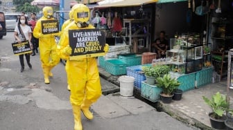 Aktivis dari People for the Ethical Treatment of Animals (PETA) menggunakan alat pelindung diri (APD) berjalan di Pasar Hewan Jatinegara, Jakarta, Selasa (12/11/2024). [Suara.com/Alfian Winanto]