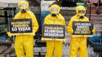 Aktivis dari People for the Ethical Treatment of Animals (PETA) menggunakan alat pelindung diri (APD) berjalan di Pasar Hewan Jatinegara, Jakarta, Selasa (12/11/2024). [Suara.com/Alfian Winanto]