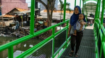 Aktivitas warga saat melewati jembatan Ijo di kawasan Batu Tumbuh, Jakarta, Rabu (13/11/2024). [Suara.com/Alfian Winanto]