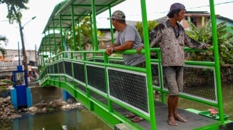 Aktivitas warga saat melewati jembatan Ijo di kawasan Batu Tumbuh, Jakarta, Rabu (13/11/2024). [Suara.com/Alfian Winanto]