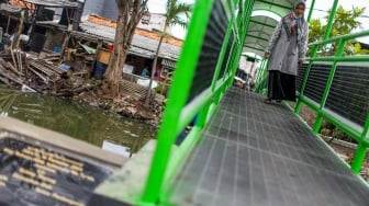 Aktivitas warga saat melewati jembatan Ijo di kawasan Batu Tumbuh, Jakarta, Rabu (13/11/2024). [Suara.com/Alfian Winanto]