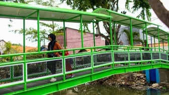 Aktivitas warga saat melewati jembatan Ijo di kawasan Batu Tumbuh, Jakarta, Rabu (13/11/2024). [Suara.com/Alfian Winanto]