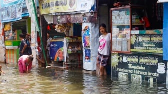 Warga beraktivitas di tengah banjir rob yang menggenangi wilayah Muara Angke, Jakarta Utara, Selasa (19/11/2024). [Suara.com/Alfian Winanto]