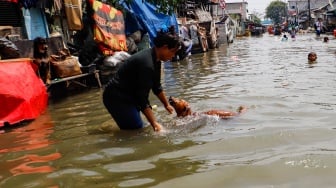 Warga beraktivitas di tengah banjir rob yang menggenangi wilayah Muara Angke, Jakarta Utara, Selasa (19/11/2024). [Suara.com/Alfian Winanto]