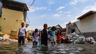 Warga beraktivitas di tengah banjir rob yang menggenangi wilayah Muara Angke, Jakarta Utara, Selasa (19/11/2024). [Suara.com/Alfian Winanto]