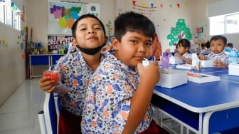 Para siswa menyantap makanan saat mengikuti uji coba Program Makan Bergizi gratis di SD Angkasa 5 Halim Perdana Kusuma, Jakarta, Selasa (26/11/2024). [Suara.com/Alfian Winanto]