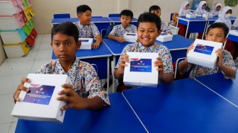 Para siswa menerima kotak makan saat mengikuti uji coba Program Makan Bergizi gratis di SD Angkasa 5 Halim Perdana Kusuma, Jakarta, Selasa (26/11/2024). [Suara.com/Alfian Winanto]