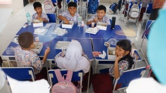 Para siswa menyantap makanan saat mengikuti uji coba Program Makan Bergizi gratis di SD Angkasa 5 Halim Perdana Kusuma, Jakarta, Selasa (26/11/2024). [Suara.com/Alfian Winanto]