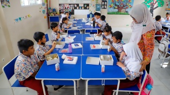 Para siswa menyantap makanan saat mengikuti uji coba Program Makan Bergizi gratis di SD Angkasa 5 Halim Perdana Kusuma, Jakarta, Selasa (26/11/2024). [Suara.com/Alfian Winanto]