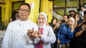 Calon gubernur (Cagub) DKI Jakarta nomor urut 1 Ridwan Kamil (kiri) bersama istri sekaligus Anggota Komisi VIII DPR RI Atalia Praratya (kedua kiri) menunjukkan tinta pada jari usai menggunakan hak pilihnya menggunakan hak pilihnya pada pilkada serentak 2024 di Tempat Pemungutan Suara (TPS) 23 Kelurahan Ciumbuleuit, Bandung, Jawa Barat, Rabu (27/11/2024). [ANTARA FOTO/Novrian Arbi]