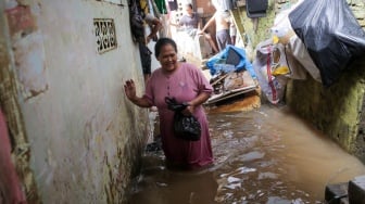 Warga beraktivitas di tengah banjir yang menggenang di wilayah Kebon Pala, Jakarta, Kamis (28/11/2024). [Suara.com/Alfian Winanto]
