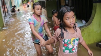 Warga beraktivitas di tengah banjir yang menggenang di wilayah Kebon Pala, Jakarta, Kamis (28/11/2024). [Suara.com/Alfian Winanto]
