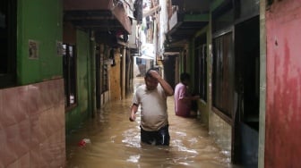 Warga beraktivitas di tengah banjir yang menggenang di wilayah Kebon Pala, Jakarta, Kamis (28/11/2024). [Suara.com/Alfian Winanto]
