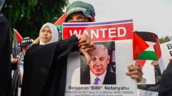 Massa mengangkat poster Netanyahu saat aksi solidaritas untuk Palestina di depan Kedutaan Besar Amerika di Jakarta, Jumat (29/11/2024). [Suara.com/Alfian Winanto]