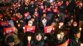 Orang-orang memegang plakat bertuliskan "Pemberontakan Yoon Suk Yeol mundur!" saat mereka ambil bagian dalam acara peringatan lilin untuk memprotes Presiden Korea Selatan Yoon di Seoul, Korea Selatan, Rabu (4/12/2024). [Philip FONG / AFP]