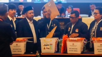 Petugas PPK Kecamatan Kemayoran membuka kotak berisi amplop form C hasil perhitungan suara disaksikan anggota KPU Kota Jakarta Pusat dan Bawaslu Kota Jakarta Pusat saat rapat pleno terbuka rekapitulasi hasil penghitungan perolehan suara dalam Pilkada serentak tahun 2024 di KotaJakarta Pusat, Rabu (4/12/2024). [Suara.com/Alfian Winanto]