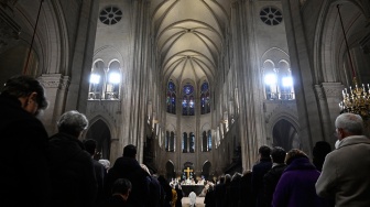 Seorang pendeta berlutut saat Uskup Agung Paris Laurent Ulrich (tengah belakang) memimpin doa untuk pentahbisan altar utama baru, selama misa dalam upacara pembukaan kembali Katedral Notre Dame di Paris, Prancis, Minggu (8/12/2024). [JULIEN DE ROSA / AFP]