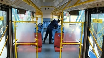 Petugas melihat kondisi di dalam bus listrik Transjakarta berjejer di Lapangan Silang Monas, Jakarta, Selasa (10/12/2024). [Suara.com/Alfian Winanto]