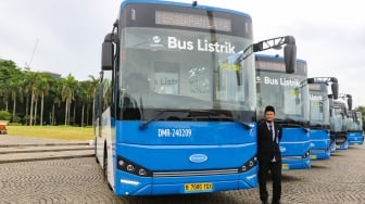 Pengemudi berdiri di depan bus listrik Transjakarta di Lapangan Silang Monas, Jakarta, Selasa (10/12/2024). [Suara.com/Alfian Winanto]