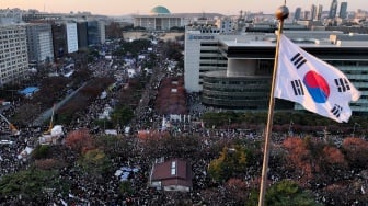 Foto udara menunjukkan bendera Korea Selatan berkibar tertiup angin saat para pengunjuk rasa yang menuntut penggulingan Presiden Yoon Suk Yeol merayakan kemenangan setelah mosi pemakzulan terhadap Yoon disahkan di luar Majelis Nasional di Seoul, Korea Selatan, Sabtu (14/12/2024). [Jung Yeon-je / AFP]