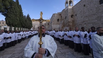 Anggota pendeta mengambil bagian dalam prosesi Natal tahunan yang dipimpin oleh Patriark Latin Yerusalem di luar Gereja Kelahiran di kota Betlehem di Tepi Barat Palestina yang diduduki Israel pada Selasa (24/12/2024). [HAZEM BADER / AFP]