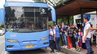 Warga antre untuk menaiki bus tingkat wisata TransJakarta di kawasan Monas, Jakarta, Kamis (26/12/2024). [Suara.com/Alfian Winanto]