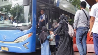 Warga antre untuk menaiki bus tingkat wisata TransJakarta di kawasan Monas, Jakarta, Kamis (26/12/2024). [Suara.com/Alfian Winanto]