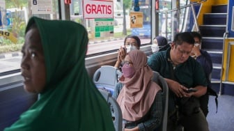 Warga menaiki bus tingkat wisata TransJakarta di kawasan Monas, Jakarta, Kamis (26/12/2024). [Suara.com/Alfian Winanto]