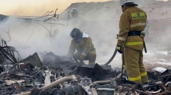 Petugas mengevakuasi puing-puing di lokasi jatuhnya pesawat penumpang Azerbaijan Airlines di dekat kota Aktau di Kazakhstan barat, Rabu (25/12/2024). [Handout / Kazakhstan's emergency situations ministry / AFP]