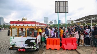 Pengunjung berwisata di kawasan Monas, Jakarta, Jumat (27/12/2024). [Suara.com/Alfian Winanto]