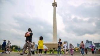 Pengunjung berwisata di kawasan Monas, Jakarta, Jumat (27/12/2024). [Suara.com/Alfian Winanto]