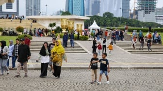 Pengunjung berwisata di kawasan Monas, Jakarta, Jumat (27/12/2024). [Suara.com/Alfian Winanto]