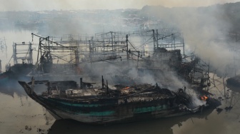 Petugas berusaha memadamkan api yang membakar kapal nelayan di Pelabuhan Tegal, Jawa Tengah, Jumat (27/12/2024). [ANTARA FOTO/Oky Lukmansyah/rwa]