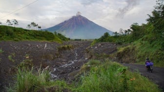 Warga melintasi jalur Curah Kobokan saat asap vulkanis keluar dari kawah Gunung Semeru terlihat dari Desa Supiturang, Lumajang, Jawa Timur, Sabtu (28/12/2024). [ANTARA FOTO/Irfan Sumanjaya/nz]