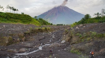 Warga melintasi jalur Curah Kobokan saat asap vulkanis keluar dari kawah Gunung Semeru terlihat dari Desa Supiturang, Lumajang, Jawa Timur, Sabtu (28/12/2024). [ANTARA FOTO/Irfan Sumanjaya/nz]