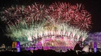 Kembang api menerangi langit tengah malam di atas Jembatan Pelabuhan Sydney dan Gedung Opera Sydney selama perayaan Tahun Baru 2025 di Sydney, Australia, Rabu (1/1/2025). [David GRAY / AFP]