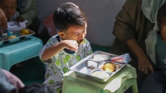 Anak-anak menyantap hidangan Makan Bergizi Gratis (MBG) di kawasan Ciracas, Jakarta, Jumat (10/1/2025). [Suara.com/Alfian Winanto]