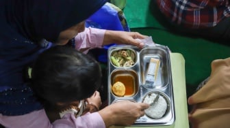 Warga menyantap hidangan Makan Bergizi Gratis (MBG) di kawasan Ciracas, Jakarta, Jumat (10/1/2025). [Suara.com/Alfian Winanto]