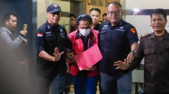 Petugas menggiring tersangka kasus dugaan suap hakim pembebas Gregorius Ronald Tannur Rudi Suparmono (tengah) keluar dari Gedung Kejaksaan Agung, Jakarta, Selasa (14/1/2025). [Suara.com/Alfian Winanto]