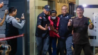 Petugas menggiring tersangka kasus dugaan suap hakim pembebas Gregorius Ronald Tannur Rudi Suparmono (tengah) keluar dari Gedung Kejaksaan Agung, Jakarta, Selasa (14/1/2025). [Suara.com/Alfian Winanto]