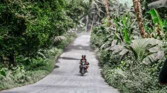 Pengendara sepeda motor melintas di jalan umum yang tertutup abu vulkanik dampak erupsi Gunung Ibu di Desa Tobaro, Kabupaten Halmahera Barat, Maluku Utara,Rabu (15/1/2025). [ANTARA FOTO/Andri Saputra/foc]