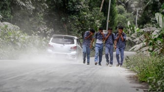 Sejumlah pelajar melintas di jalan umum yang tertutup abu vulkanik dampak erupsi Gunung Ibu di Desa Tobaro, Kabupaten Halmahera Barat, Maluku Utara,Rabu (15/1/2025). [ANTARA FOTO/Andri Saputra/foc]