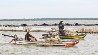 Nelayan melintas di depan pagar laut yang berada di kawasan perairan Tarumajaya, Bekasi, Jawa Barat, Kamis (16/1/2025). [Suara.com/Alfian Winanto]