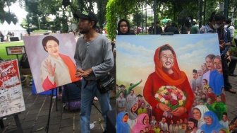 Warga melihat lukisan wajah Megawati Soekarnoputri yang terpajang di Taman Suropati, Jakarta, Kamis (23/1/2025). [Suara.com/Alfian Winanto]