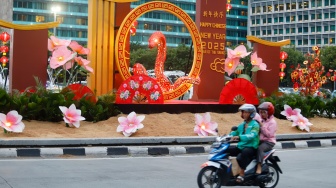 Sejumlah pengendara sepeda motor melintasi dekorasi Tahun Baru Imlek di Bundaran HI, Jakarta, Senin (27/1/2025). [Suara.com/Alfian Winanto]